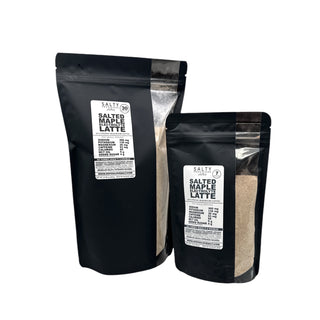 Two pouches of SALTED MAPLE ELECTROLYTE LATTE mix, one with a clear window showing the product inside, the other is black with label details.